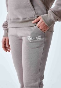 Lichtgrijze katoenen sweatpants met een strakke pasvorm, voorzien van een zijzak en witte borduursel "Project + Paris" op de dij.