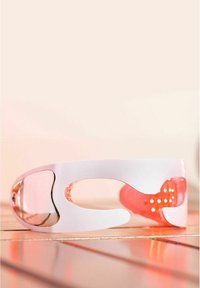 Lunettes de soleil blanches avec des verres roses transparents. Présentent un design unique avec des découpes et une surface lisse et brillante. Accentuées par des trous ronds sur les branches.