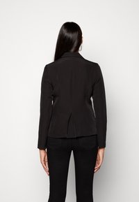 Czarna dopasowana marynarka z długimi rękawami i klapami, z tylnym rozcięciem dla swobody ruchów oraz gładką fakturą.