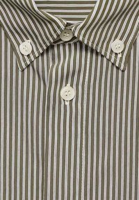 Chemise marron boutonnée avec de fines rayures verticales blanches et des boutons blancs sur le col et au centre devant.