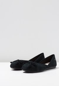 Černé semišové baletní byty s kulatou špičkou, dekorativní mašlí a nízkou flexibilní podrážkou. Mírný lesk, hladká textura.