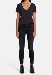 Black V-neck t-shirt paired with dark skinny jeans. The fabric is smooth; jeans have a classic five-pocket design and a fitted shape.