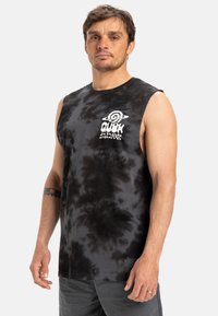 Black tie-dye sleeveless shirt with Quiksilver logo, round neckline, and soft texture. Model wears gray pants, standing against a white background.