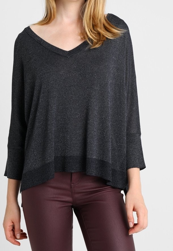 Czarny, luźny sweter z dekoltem w serek, rękawami do połowy przedramienia i żebrowanym dołem. Tkanina ma subtelny połysk. Połączony z bordowymi spodniami.