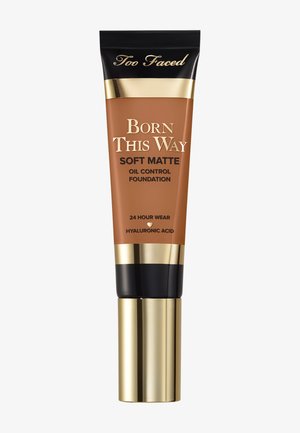 Too Faced Born This Way Soft Matte Foundation in einer braunen Tube mit goldenen Akzenten, ausgestattet mit einem schwarzen Deckel und Etiketten, die Ölkontrolle und 24-Stunden-Tragekomfort anzeigen.