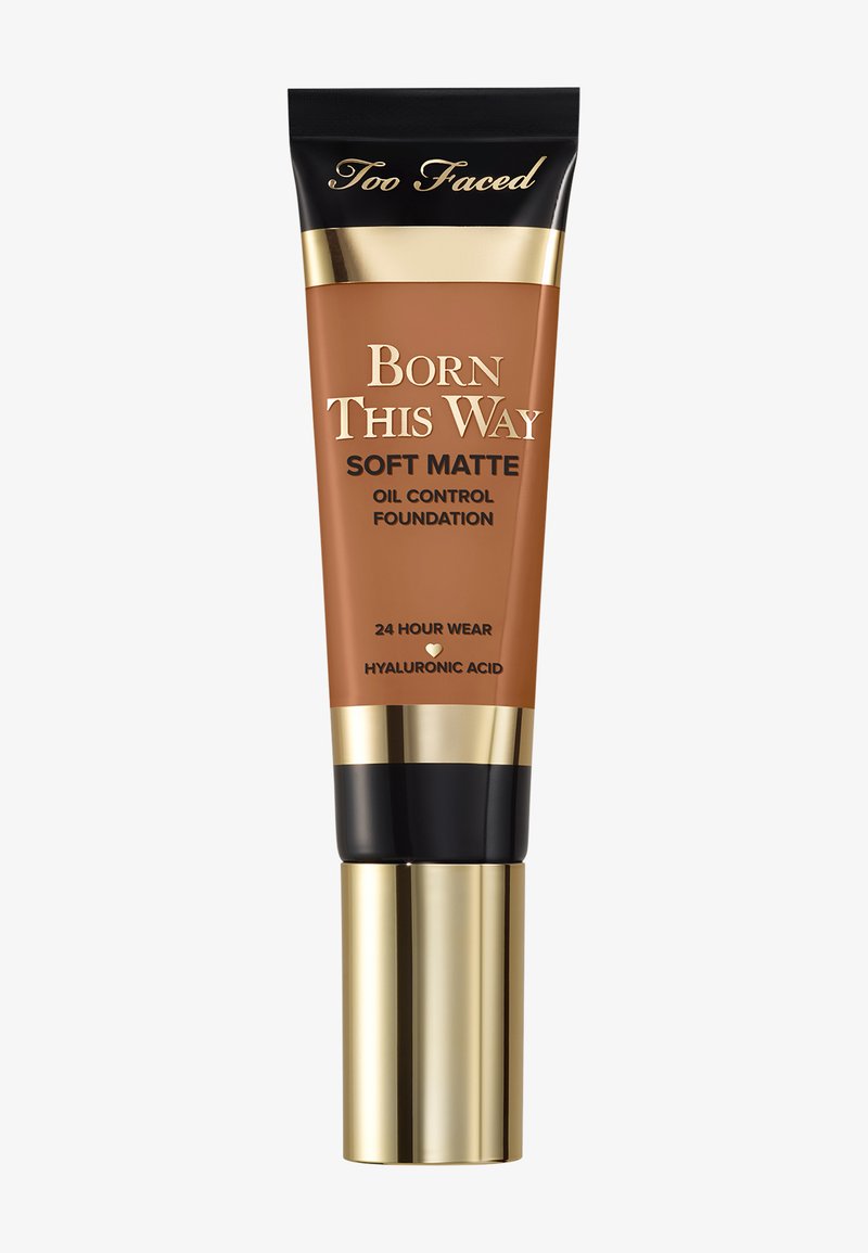 Too Faced Born This Way Soft Matte Foundation in a brown tube with gold accents, featuring a black cap and labels indicating oil control and 24-hour wear.