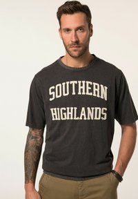 Tmavě šedé bavlněné tričko s nápisem "SOUTHERN HIGHLANDS" v krémových písmenech. Krátké rukávy a kulatý výstřih, s volným střihem.