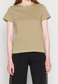 Randig kortärmad t-shirt i beige och mörk khaki, med rundad hals och liten orange logotyp på vänster bröst. Mjukt bommaterial.