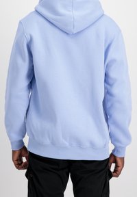 Sudadera con capucha azul claro hecha de tela suave, con bolsillo tipo canguro, puños y dobladillo acanalados, y capucha con cordón ajustable.
