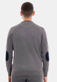 Maglione grigio con maniche lunghe, colletto rotondo e toppe blu sui gomiti. Polsini e orlo a coste, texture liscia. Vista posteriore.