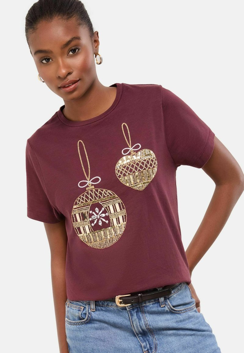 Bordeaux värvi lühikeste varrukatega T-särk, millel on kuldsed jõulukaunistuste trükised koos kaunistustega. Pehme puuvillane kangas, lõdva lõikega ja ümmargune kaelus.