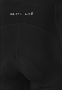 Pantaloni da ciclismo neri realizzati in un tessuto morbido e elastico. Caratteristiche includono cuciture piatte e aree imbottite per il comfort, con il testo brandizzato "ELITE LAB".