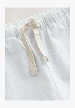 Tela de lino blanco con una superficie texturizada, que presenta un cierre de cordón en color beige natural, atado en un nudo a la altura de la cintura.