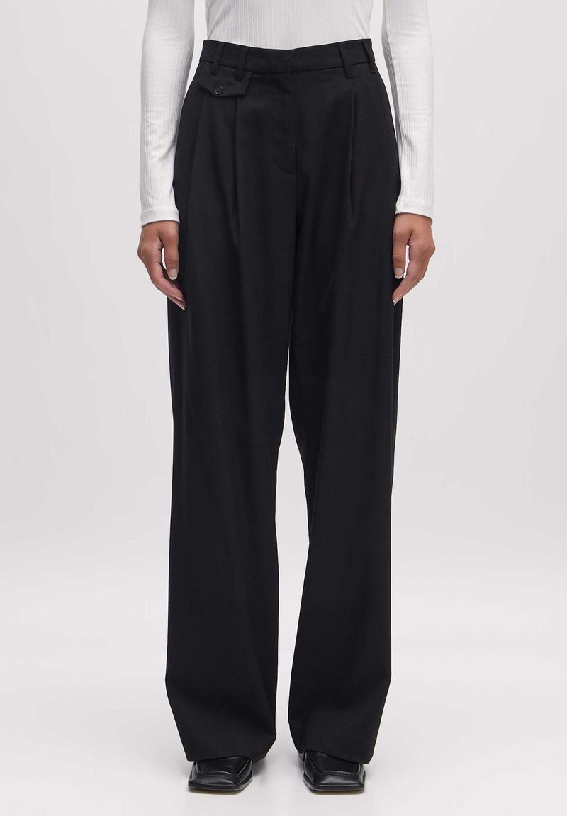 Zwarte geplooide broek met een hoge taille, gemaakt van een soepele stof. Beschikt over een schuine zak en een ontspannen, brede pasvorm.