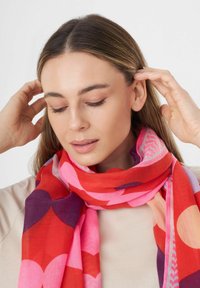 Écharpe multicolore avec des motifs de cœurs et de cercles en rouge, rose et violet, dotée d'une texture douce et d'un design léger.