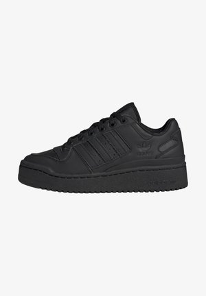 Baskets basses noires Adidas avec une semelle épaisse, lacets à l'avant et les trois bandes emblématiques sur le côté.