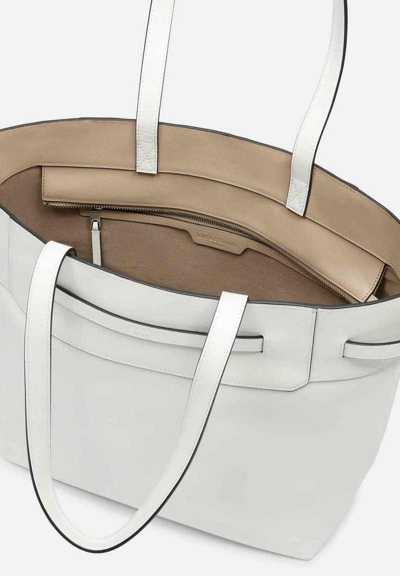 Weiße Leder-Tragetasche mit abgerundeten Griffen, Innenfächern und einem beigen Innenfutter. Verfügt über kontrastierende Nähte und ein Reißverschlussfach.