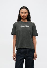 Dark gray cotton T-shirt with short sleeves, featuring a white "Tommy Hilfiger" logo, decorative gold buttons on the shoulder, and a relaxed fit.