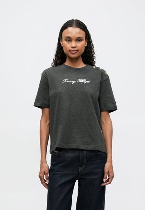 Σκοτεινό γκρι βαμβακερό T-shirt με κοντά μανίκια, που διαθέτει λευκό λογότυπο "Tommy Hilfiger", διακοσμητικά χρυσά κουμπιά στον ώμο και άνετη εφαρμογή.
