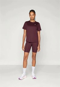 Burgunder atletisk t-skjorte og matchende sykkelshorts, laget av lettvektig stoff. Har korte ermer og en liten logo på brystet.