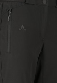 Sorte bukser med lynlåslomme i siden og knaplukning, med et diskret trekantet flammelogo på låret.