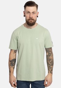 Lichtgroenes T-shirt met korte mouwen en een ronde hals, voorzien van een klein wit logo op de borst. Zacht katoen materiaal; comfortabele pasvorm.