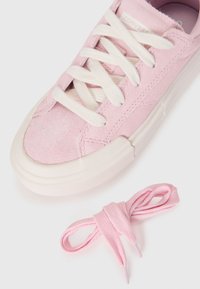 Baskets en daim rose avec lacets blancs et semelle en caoutchouc ; dotées de coutures décoratives et d'une texture lisse. Comprend des lacets assortis roses.