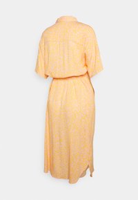 Vestido amarelo com um padrão em rosa claro. Apresenta colarinho, mangas curtas, um laço na cintura e fendas laterais para facilitar o movimento.