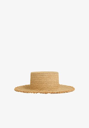 Chapeau bateau en paille avec couronne plate et large bord légèrement effiloché, tissé en fibres beiges naturelles.