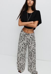 Zwarte cropped top gecombineerd met wijde broek met een zwart-wit zebra print. Elastische tailleband met trekkoorddetail.