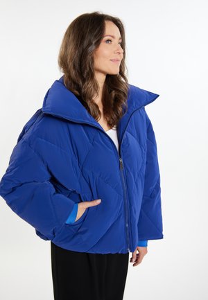 Blauwe pufferjack met een geometrisch gewatteerd patroon, een oversized kraag en een ritssluiting. Bevat zijzakken en contrasterende manchetten.