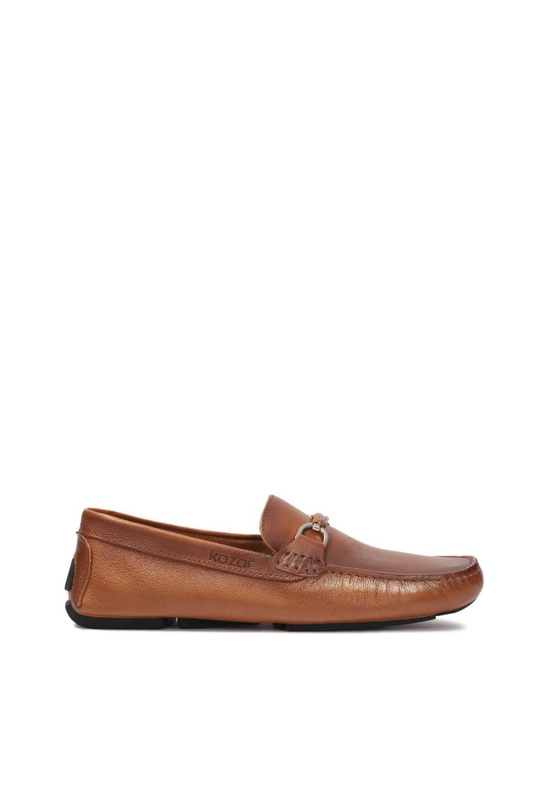 Mocasines de cuero marrón, sin cierre, con punta redondeada, un sutil brillo, detalle decorativo de borlas y suela de goma negra.