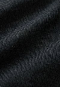 Gros plan d'un tissu tissé noir montrant une texture détaillée et de subtiles réflexions de lumière sur la surface.