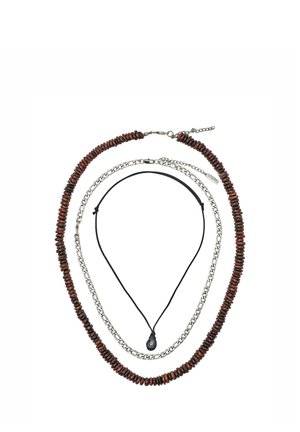 Trois colliers superposés : extérieur avec des perles en bois brun foncé, milieu avec des maillons de chaîne en argent, intérieur avec un cordon noir et un pendentif en pierre noire.