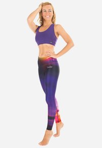 Paarse sportbeha gecombineerd met hoge tailleleggings in een gradiënt van paarse, zwarte en oranje tinten. Glad, rekbaar materiaal.