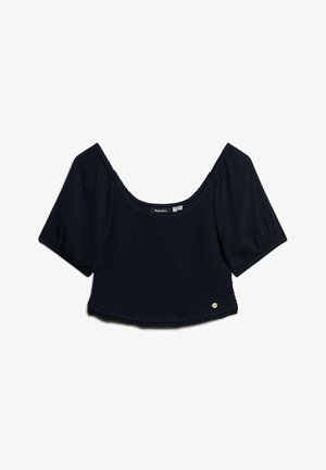 Granatowy krótki top z krótkimi puffami, teksturowana tkanina i szeroki dekolt. Posiada mały akcent logo w pobliżu dołu.