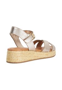 Wedge sandal with beige leather straps, gold buckle, and woven straw platform sole.