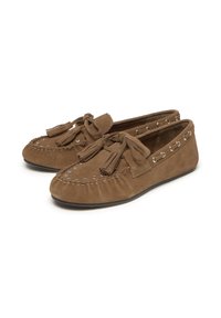 Zapatos de mocasín de gamuza marrón presentan una puntera redondeada, borlas decorativas y acentos de ojales plateados a lo largo de los lados.