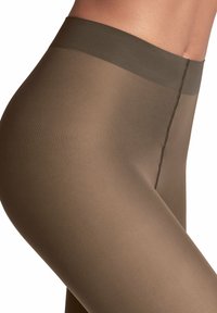 Transparante bruine panty's met een gladde textuur en een brede tailleband, met een centrale naad die verticaal langs het been loopt.