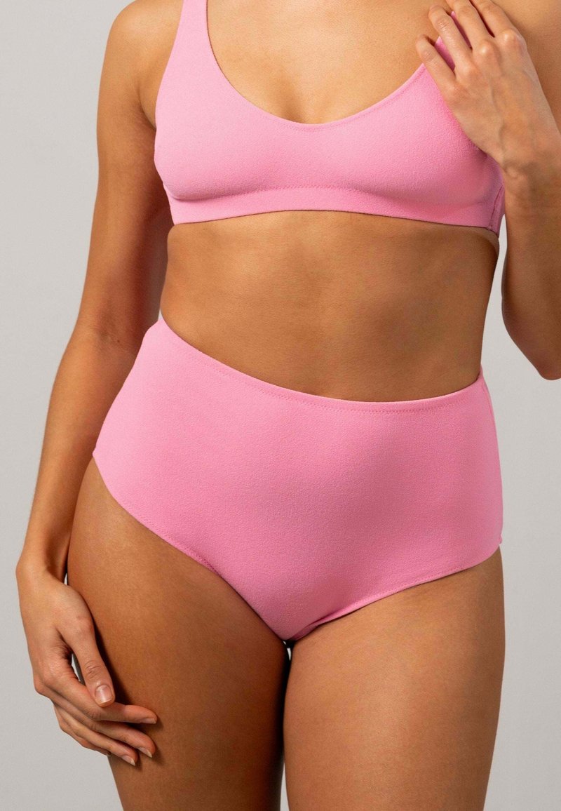 Rosa sportbh och högmidjade trosor i set, sömlös design, slät textur och enkla silhuetter utan ytterligare mönster eller detaljer.