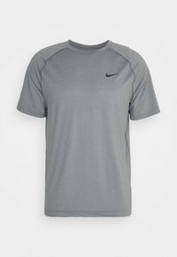 Camiseta atlética gris de mangas cortas con un sutil patrón texturizado y un pequeño logo de Nike en negro en la parte superior izquierda del pecho.