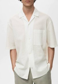 Korte mouwen shirt van gestructureerde witte stof, met een kraag en een borstzakje. Ontspannen pasvorm met subtiele verticale lijnen.