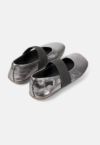 Metallic sølv ballet flats med en elastisk sort rem over vristen, tekstureret overdel med en glat tå og en fleksibel sål.