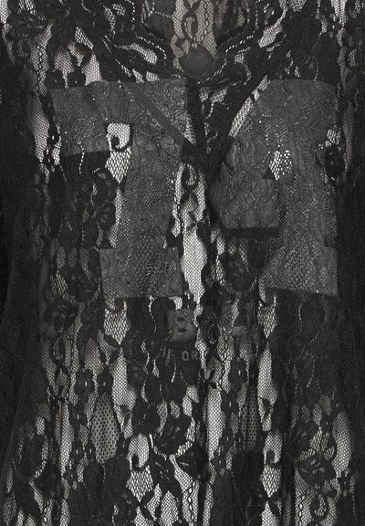 Vêtement en dentelle noire présentant des motifs floraux complexes. Tissu transparent avec un décolleté en V et des détails de boutons le long du devant.