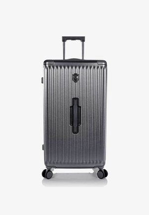 Valise à coque dure gris foncé avec des rainures verticales, quatre roulettes pivotantes, une poignée télescopique et une poignée supérieure encastrée.