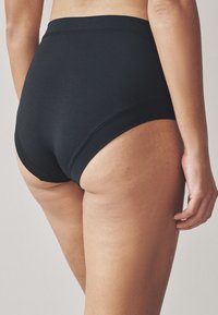 Czarne bawełniane majtki z wysokim stanem charakteryzują się gładką fakturą, elastyczną talią oraz bezszwowym designem z tylnym pokryciem.