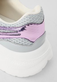 Baskets grises et pastel avec un dessus en maille, des accents métalliques roses et une semelle blanche texturée. Elles disposent d'un col rembourré pour plus de confort.