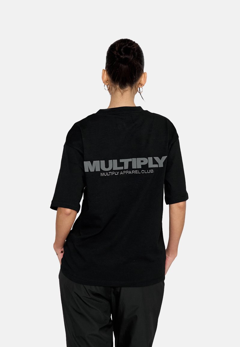 Sort bomulds T-shirt med korte ærmer, der har stor grå tekst "MULTIPLY" og "MULTIPLY APPAREL CLUB" nedenunder på ryggen.