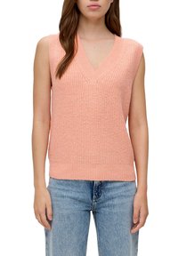 Maglione senza maniche in maglia pesca con scollo a V, motivo strutturato e orlo a costine, abbinato a jeans blu chiaro.