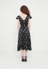 Μαύρο φόρεμα με λουλούδια, κοντά μανίκια, ντεκολτέ με v στην πλάτη, σφηκοφωλιά στη μέση και ποδό γυρος με βολάν. Διακοσμημένο με μικρές βούλες και διακοσμητικό λουλουδάτο μοτίβο.